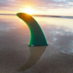 single fin fiberglass in sand sunset