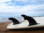 single tab black fins in surfboard on beach