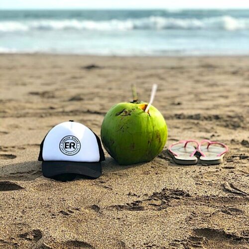 trucker hat on beach with coconut and flip flops